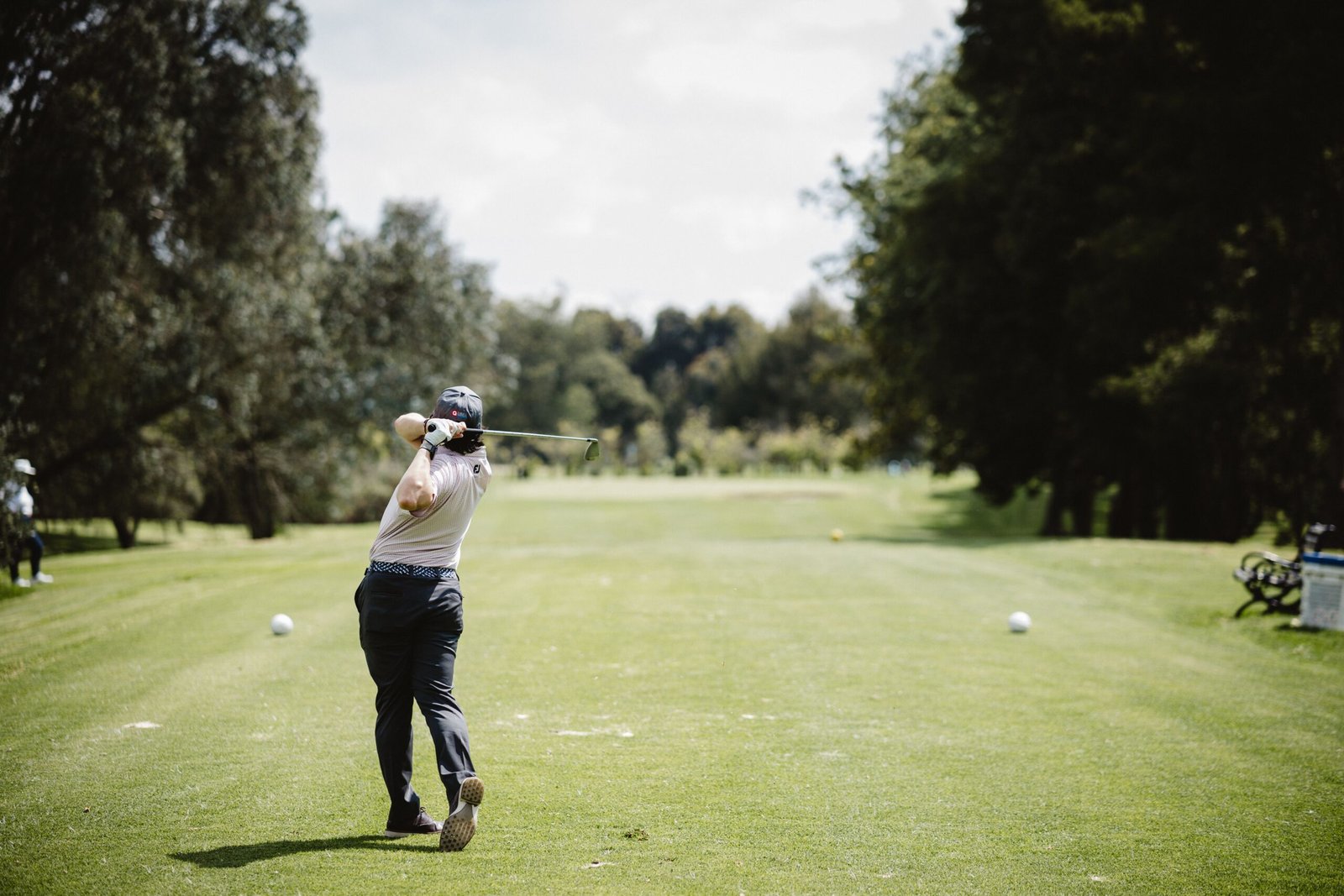 A golfer swings on a bright day in Bogotá, Colombia's lush green golf course.